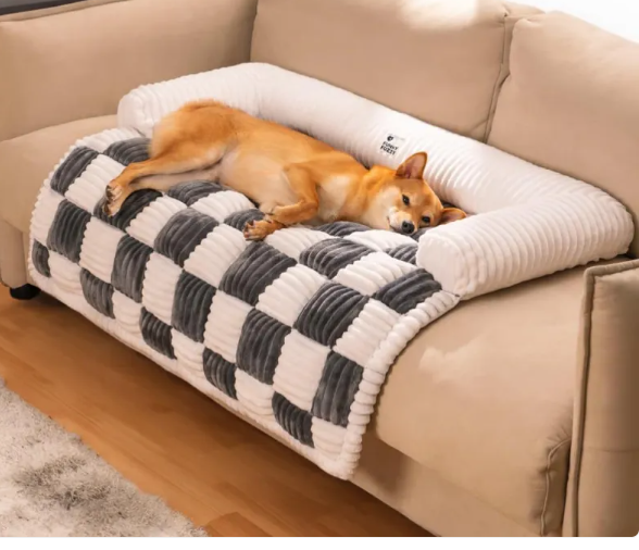 A shiba inu dog sleeps on a couch on a Creative Critters CozyPlush Pet Bed, a plush grey and white checkered blanket with a white U-shaped bolster.